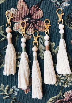 four tasseled key chains hanging on a floral fabric with gold metal clasps