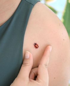 a ladybug tattoo on the back of a woman's left shoulder and arm