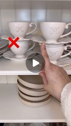 a person is pointing at dishes on the shelf