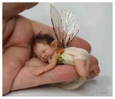 a hand holding a tiny baby doll in it's palm with stars on the background