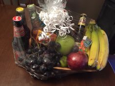 a basket filled with fruit and drinks on top of a wooden table