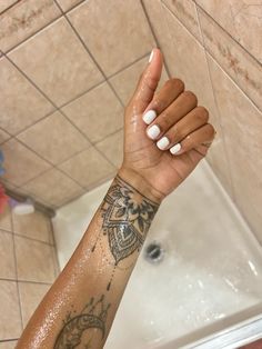 a woman's arm with a tattoo on it in front of a bathtub