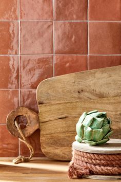 an artichoke is sitting on top of a wooden board next to a spool of twine