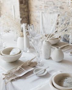 the table is set with white dishes and place settings