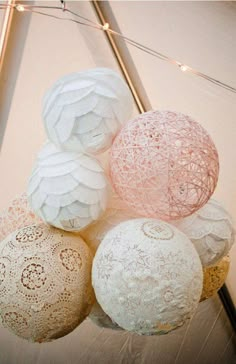 several decorative balls hanging from the ceiling in a room with string lights and lace doily