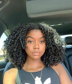 a woman sitting in the back seat of a car with her hair styled into an afro