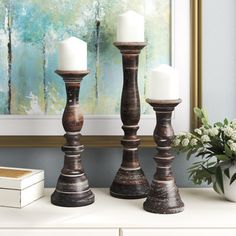 three candles sitting on top of a white dresser