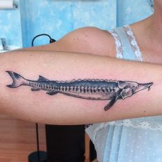 a woman with a fish skeleton tattoo on her arm