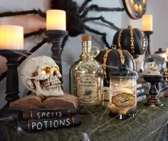 a table topped with bottles and candles next to a skull