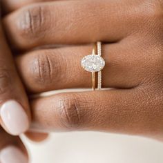 a woman's hand with a diamond ring on her left hand and the other hand holding an engagement ring