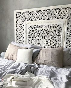 a white headboard sitting on top of a bed next to pillows and blankets in a bedroom