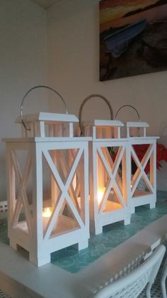 three white lanterns sitting on top of a table