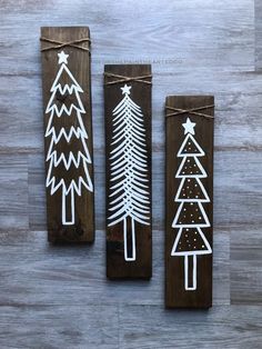 three wooden christmas trees painted with white paint on top of a wood planked floor