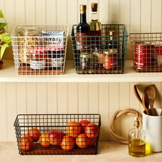 two metal baskets filled with apples sitting on top of a shelf next to bottles and utensils