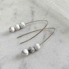 Sleek and simple threader earrings! The marble-looking gemstones are made from a natural stone called howlite.  Howlite is a mineral found in sedimentary rock... and it was actually first discovered in Canada!  History aside, these earrings are stunning to look at and extremely comfortable to wear.  I've created them with a matte finish to really bring out that bold marble look. I used nickel free silver for my ear wires because it's typically hypoallergenic and because Silver is a sustainable resource. The silver I used here is sustainable because the metal used in my jewellery can always be upcycled, recycled or melted down to create something new! I only use high-quality precious metals manufactured in the United States. To care for this item, simply buff it with a polishing cloth whene Bold Marble, Canada History, Marble Earrings, Sedimentary Rocks, Lightweight Earrings, Threader Earrings, Earrings Statement, Light Weight Earrings, Silver Wire