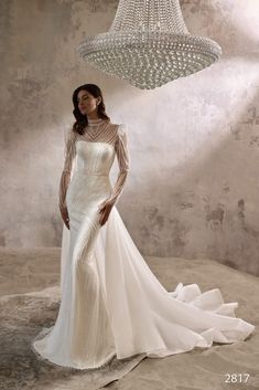 a woman in a wedding dress standing next to a chandelier