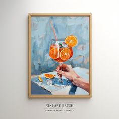 a painting hanging on the wall above a table with two glasses of wine and orange slices