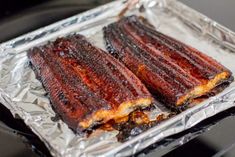 two barbecue ribs on tin foil sitting on top of an oven burner, ready to be cooked