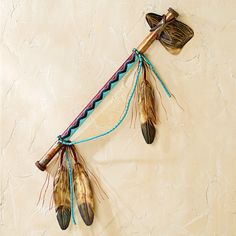 a wall hanging with feathers attached to it's sides and two arrows on the side