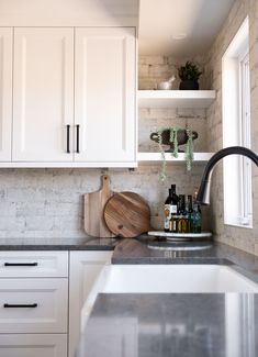 a kitchen with white cabinets and black counter tops, including a cutting board on the sink