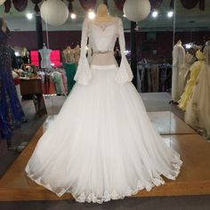 a white wedding dress is on display in a room with other gowns and dresses