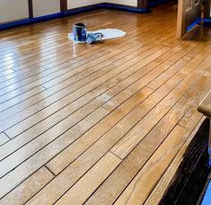 a wooden floor with a can of paint on the ground next to an open door