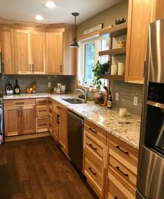 a kitchen with wooden cabinets, stainless steel appliances and wood flooring is pictured in this image