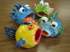 four colorful ceramic fish sitting on top of a wooden table