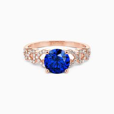 a rose gold ring with a blue stone surrounded by diamonds