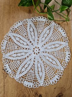 a white doily sitting on top of a wooden table next to a potted plant