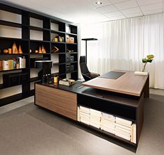 an office with black and wood furniture, bookshelves and shelves filled with papers