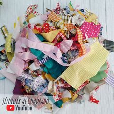 a pile of colorful fabric scraps sitting on top of a wooden floor next to a video player