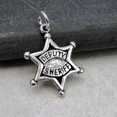 "This Deputy Sheriff Charm comes with a silver jump-ring as pictured. Please note that photo is not to scale and may appear larger to show detail. Refer to exact measurements below. Additional attachments (lobster clasp, large-hole bead, necklace chains) are available from the charm-attachments drop-down menu.  For a visual example of the different attachments and what each one is best suited for, scroll through the photos until you see the example photo or visit https://etsy.me/2BY7DAW for detailed information.    { DETAILS } ★ Material: Sterling Silver ★ Finish Color: Silver  ★ Measurements: 5/8\" x 3/4\" ★ Dimensions: One-sided ★ Made in the USA { SIMILAR ITEMS }  More deputy and police themed items available from my shop: https://www.etsy.com/shop/treasuredcharms/search?search_query=po Silver Star Of David Jewelry With Charms, Personalized Star-shaped Sterling Silver Jewelry, Silver Star Charm Symbolic Jewelry, Silver Symbolic Star Charm Jewelry, Sterling Silver Star Of David Charms Jewelry, Star-shaped Sterling Silver Jewelry With Lobster Clasp, Silver Symbolic Jewelry With Star Charm, Personalized Sterling Silver Charms For Collectors, Silver Star-shaped Charm Necklace