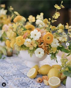 an arrangement of flowers and lemons on a table