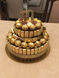 a three tiered cake made out of chocolates and wrapped in gold foil with the number 20 on top