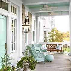 the front porch is decorated in pastel colors and has two wicker chairs on it