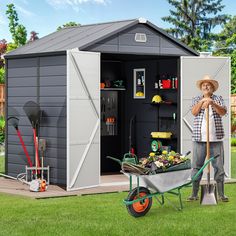 a man standing next to a wheelbarrow in front of a shed with gardening supplies