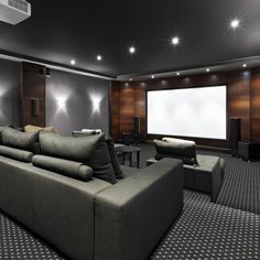 a living room with couches and chairs in front of a projector screen on the wall