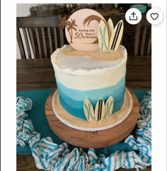 a three tiered cake with blue and white frosting sitting on top of a wooden table