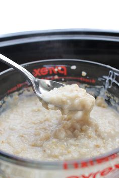 a spoon full of oatmeal is being held up by a plastic container