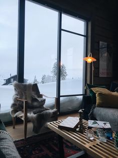 a living room filled with furniture and a large window overlooking the snow covered mountain range