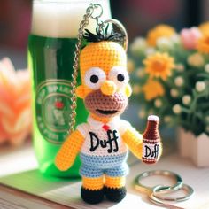 a crocheted simpsons keychain holding a beer