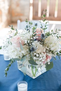 a vase filled with white and pink flowers on top of a blue table cloth