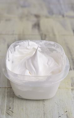 a plastic container filled with whipped cream on top of a wooden table