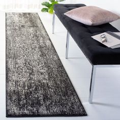 a black and white area rug on the floor next to a bench with a plant in it