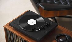 a record player sitting on top of a wooden table next to a black leather chair