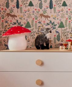 a stuffed animal sitting on top of a dresser next to a wallpapered wall