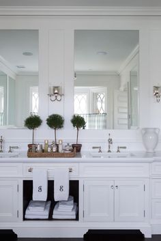 a white bathroom with double sinks and mirrors