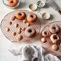 two trays with donuts sitting on top of a table next to bowls and utensils