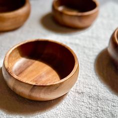 several wooden bowls sitting on top of a white cloth covered table next to each other